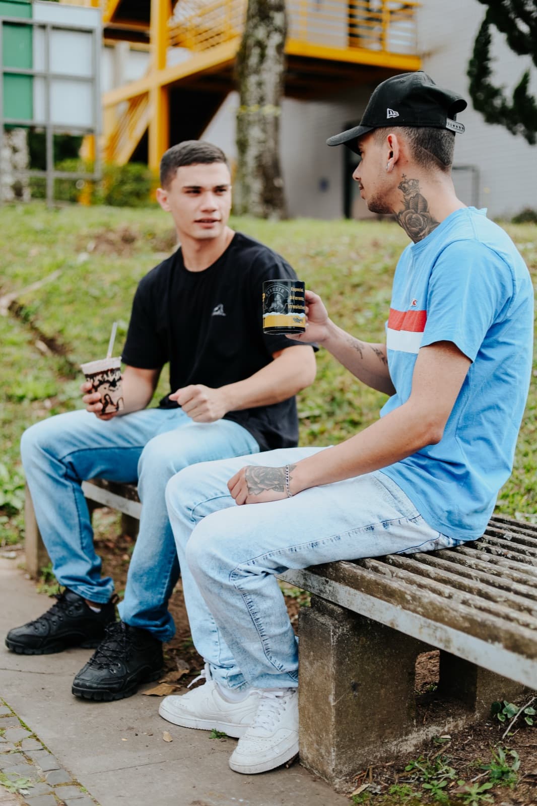 Dois universitários conversando no banco com bebidas Robusta